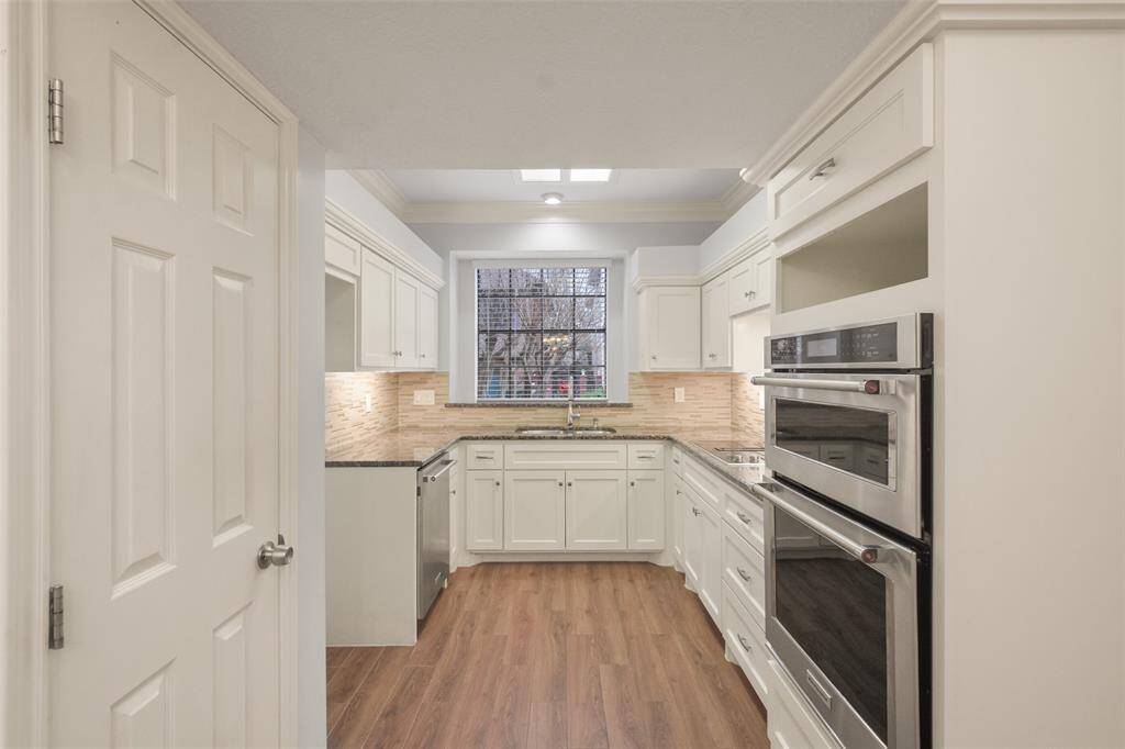 The kitchen boasts white wood cabinets, granite countertops, a double oven/microwave, and stainless steel appliances, all seamlessly connected to the breakfast area for effortless functionality and style.