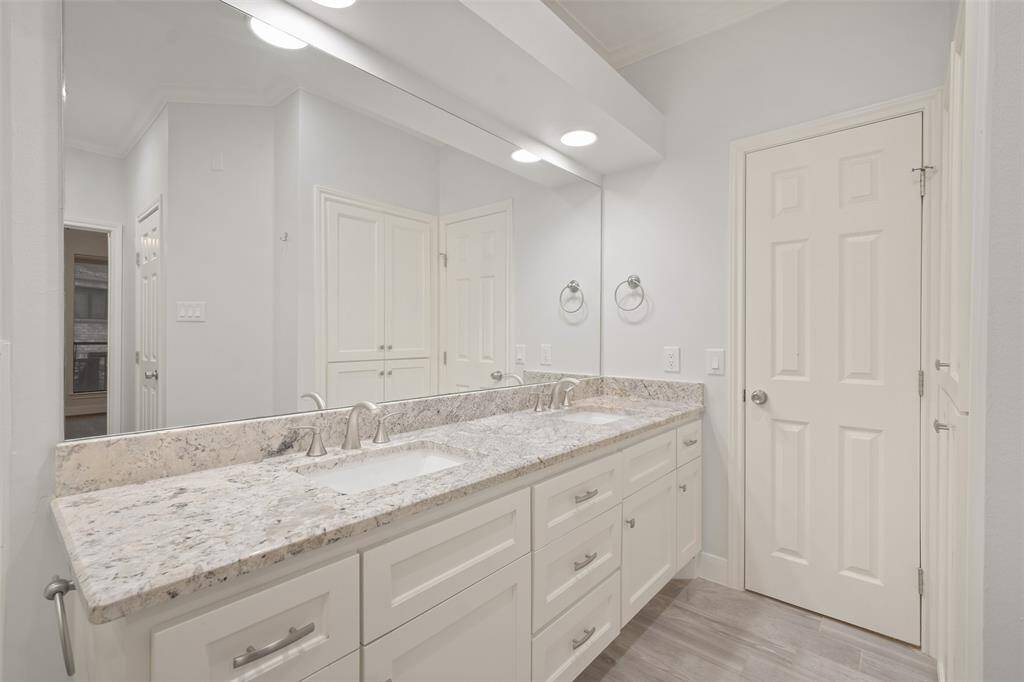 Another view of the his-and-hers sinks with door leading to a spacious walk-in closet.
