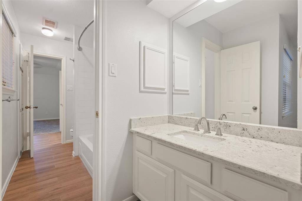 A view of the stylish sink area with granite countertops in the shared Jack-and-Jill bathroom of the 1st secondary bedroom.