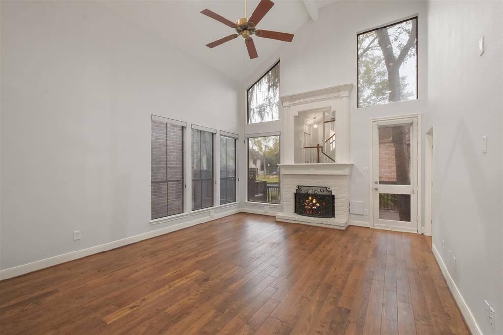 Another stunning perspective of the two-story living room, showcasing its soaring windows with breathtaking views of the serene community lake.