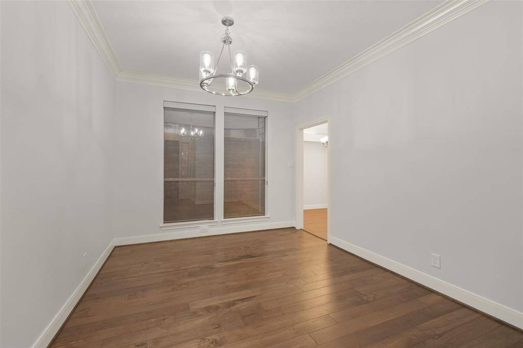 A welcoming dining room featuring classic crown molding, a custom chandelier, and windows that offer lovely views of the patio.