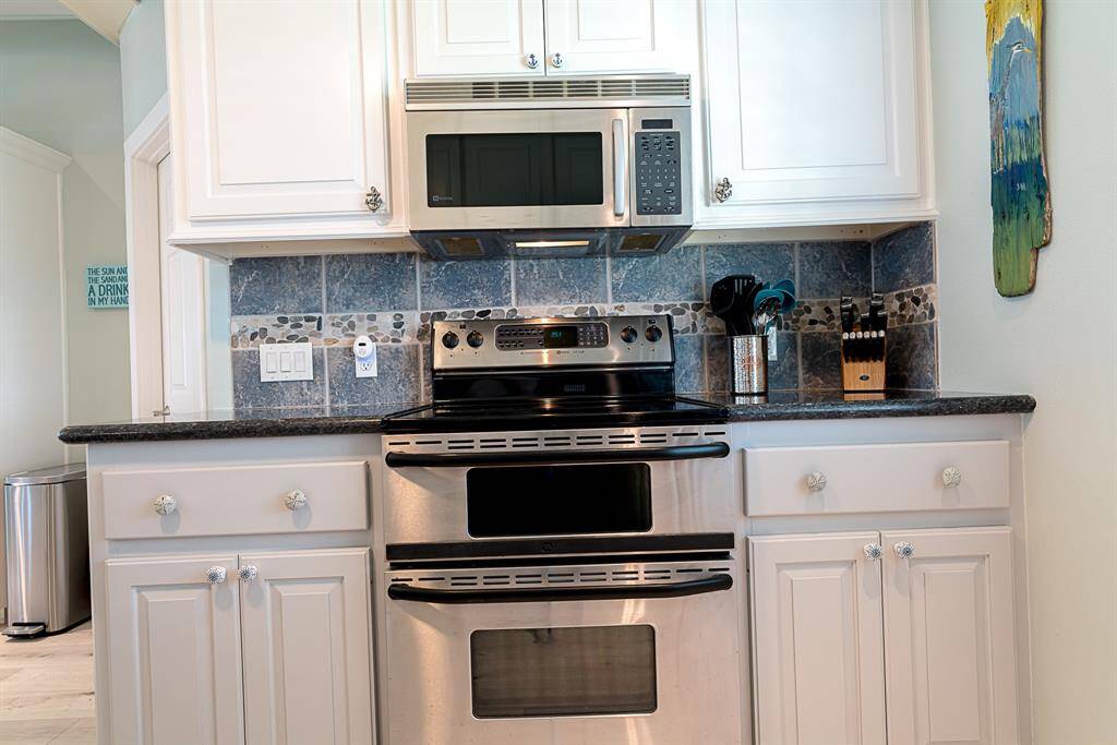 Kitchen with designer tile backsplash.  Utility room with separate entry around left corner of kitchen.