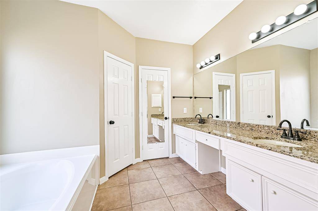 Primary bathroom features granite counters, dual sinks, vanity space, large jacuzzi tub and separate shower.