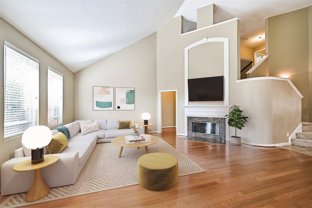 Spacious living room features a gas fireplace, wood floors, soaring ceiling & open concept living. Virtually staged.