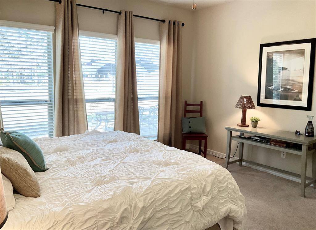 The primary bedroom features large windows with beige curtains, allowing plenty of natural light.