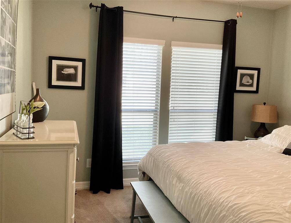 The secondary bedroom features a cozy setup, natural light streams in through the windows with blinds, completing the inviting atmosphere.