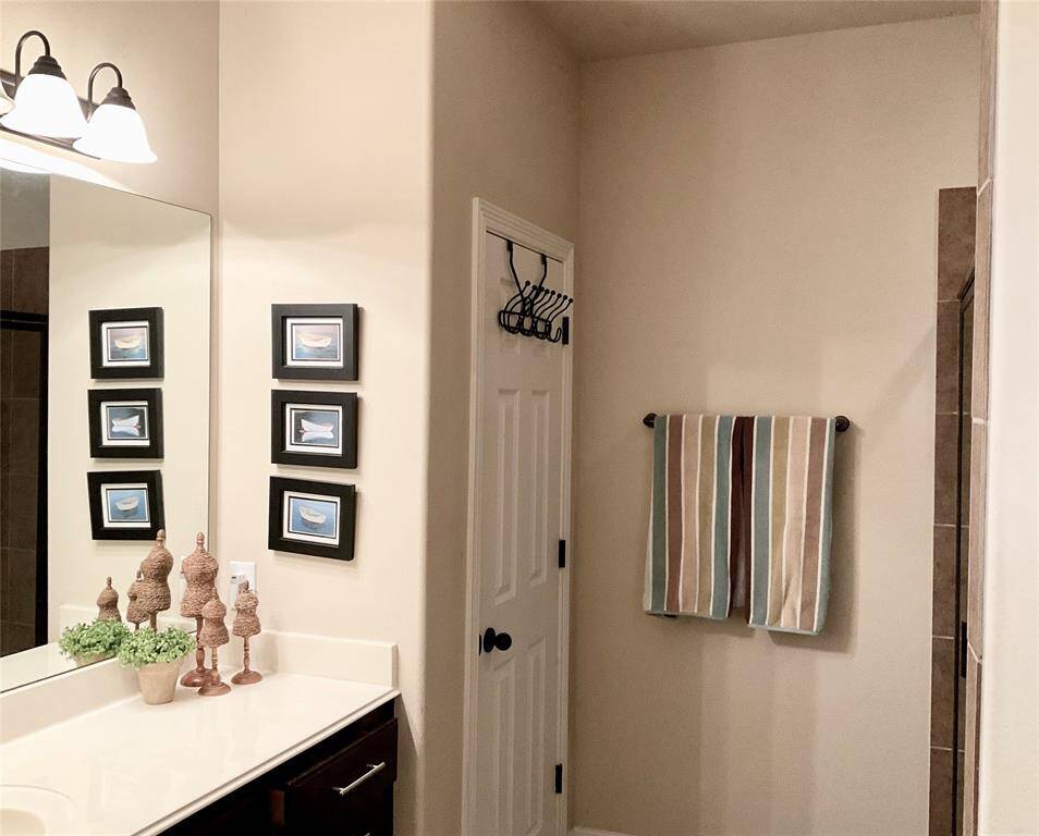 The bathroom features a modern design with a large mirror, elegant lighting, and a sleek vanity. Neutral tones create a calm and inviting atmosphere.