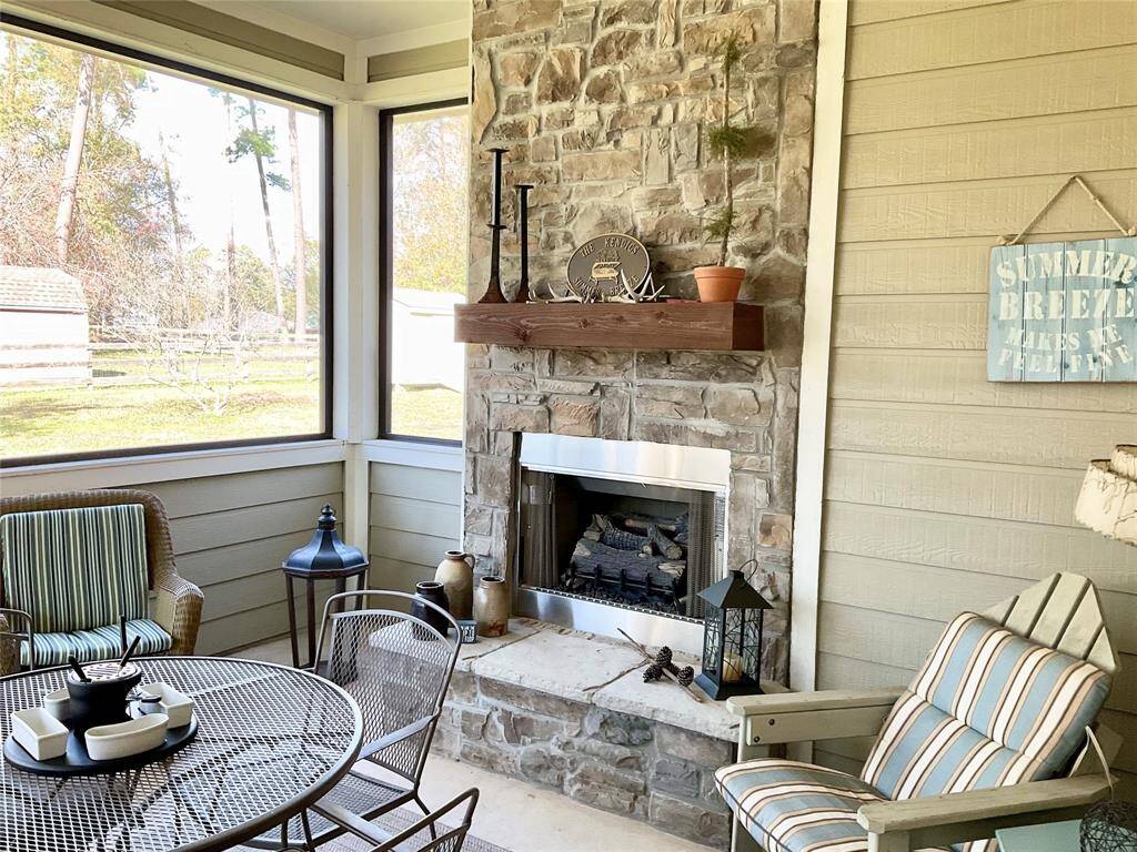 This cozy outdoor patio features a charming stone, wood burning fireplace, comfortable wicker seating, and a round table with metal chairs, offering a perfect space for relaxation and entertaining. The furnishings can remain or be removed as you desire.