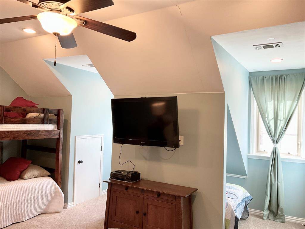 This cozy space offers sloped ceilings, recessed lighting, and a window with sheer curtains, creating a bright and inviting atmosphere.  A wonderful room with flexible enjoyment.