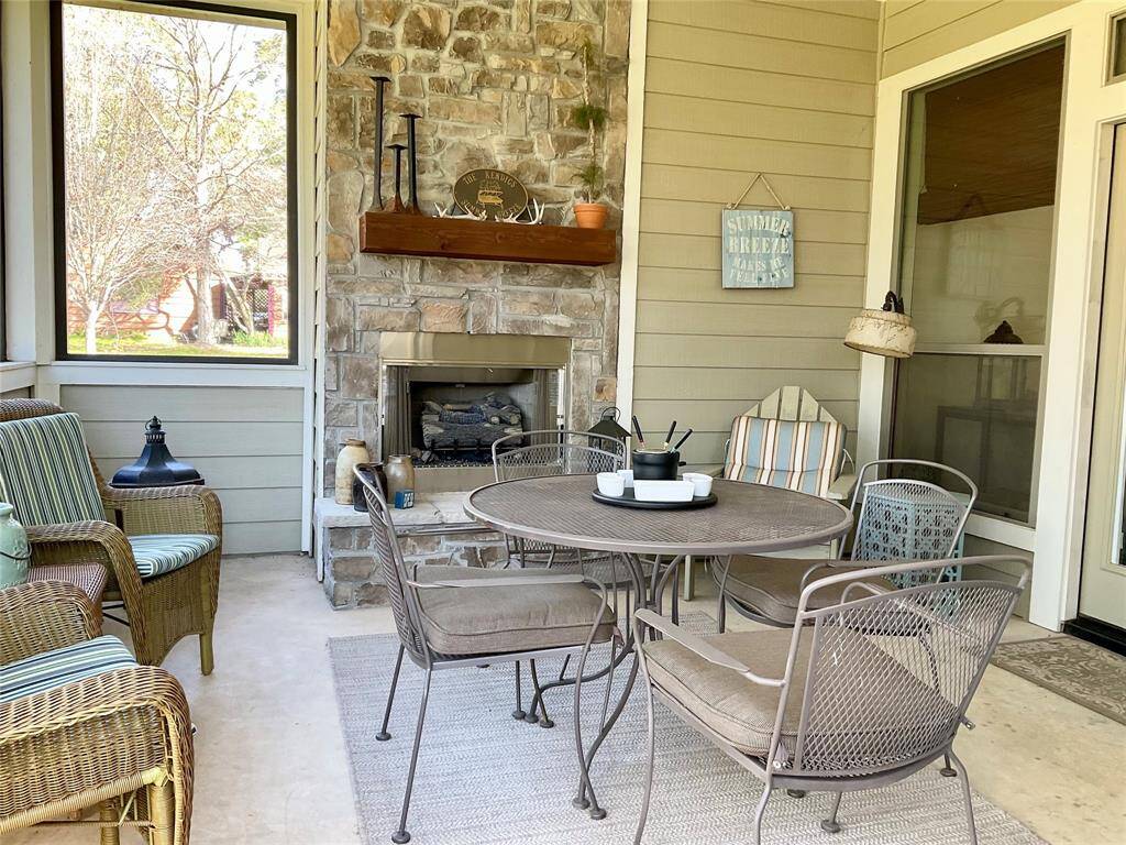 This cozy outdoor patio features a charming stone, wood burning fireplace, comfortable wicker seating, and a round table with metal chairs, offering a perfect space for relaxation and entertaining.  The furnishings can remain or be removed as you desire.