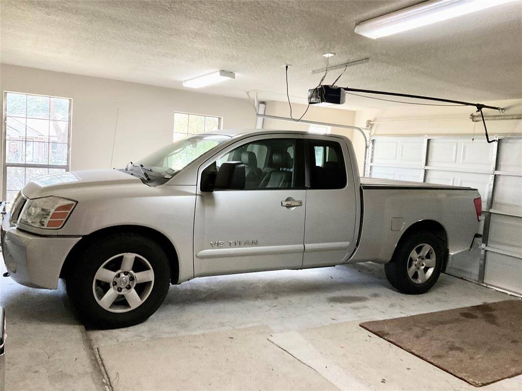 Spacious two-car garage with natural light from side windows, featuring a vehicle parked inside. The garage is equipped with overhead lighting and an automatic door opener.