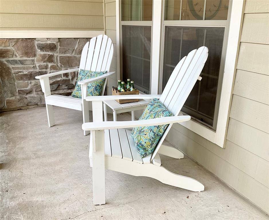 This cozy patio features two Adirondack chairs with colorful cushions, a small table, and a charming railing. It offers a welcoming outdoor space, perfect for relaxation and enjoying the fresh air. The siding and stone accents add a warm, inviting touch.
