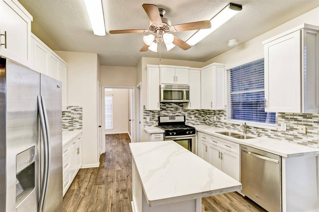 Kitchen has custom cabinets, quartz counters, glass tile backsplash and stainless appliances. Refrigerator is included!