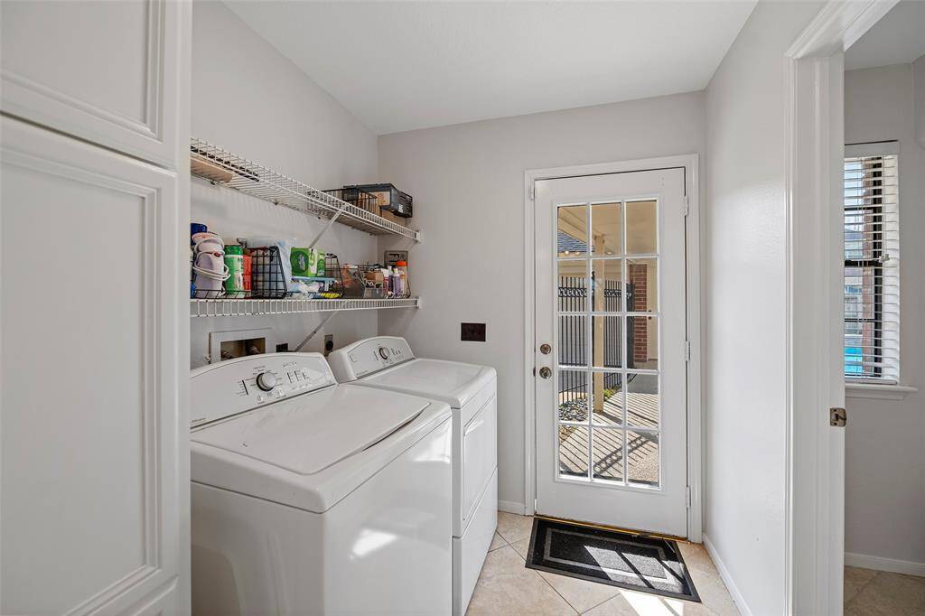 Just off the kitchen is the utility room with direct access under the breezeway to the garage! Cabinets and shelving provide plenty of storage space too!