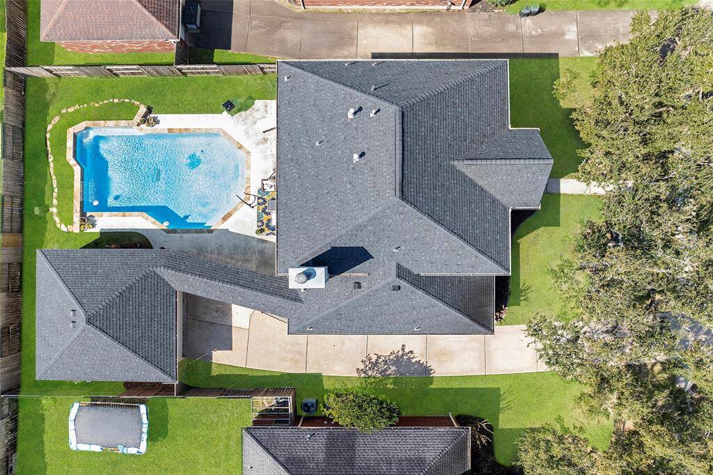 This aerial view shows the long driveway that leads to the detached garage, and the wonderful breezeway keeping you dry for grocery hauls in the rain! But let's not forget to mention the sparkling pool that will surely give you and those you hold dear a play to place on a hot Texas summer day!