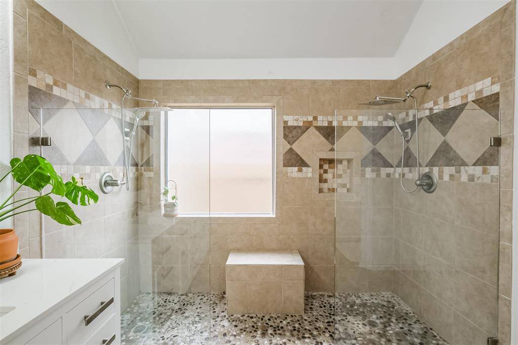 Large tile, with inlay design, large window, bench, and dual frameless glass panes allow for an elegant style.