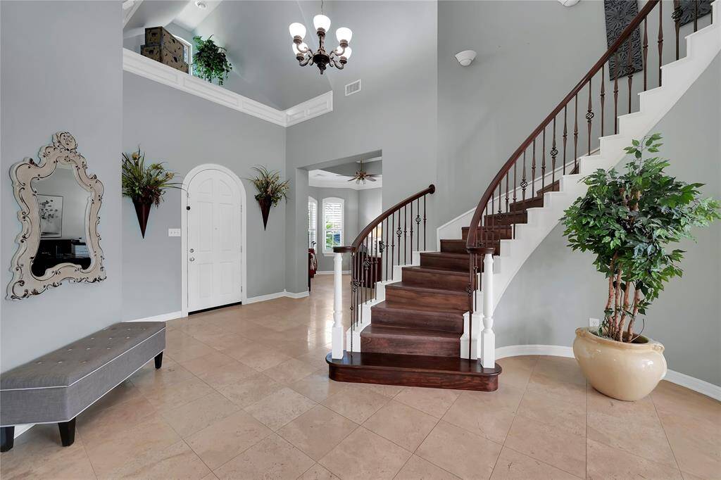 Grandiose foyer offers elevated ceilings, travertine tile, double-crown molding, spiral wood-tread staircase and wrought iron spindles... truly a touch of elegance.