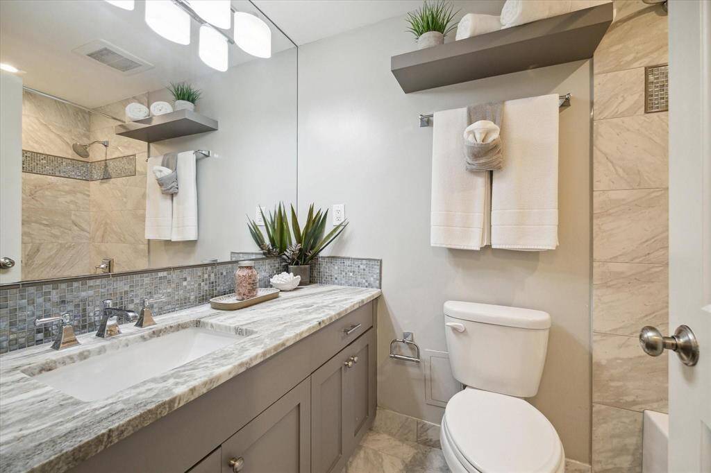 Crisp, clean Secondary Bathroom features neutral tones and stunning marble countertops.
