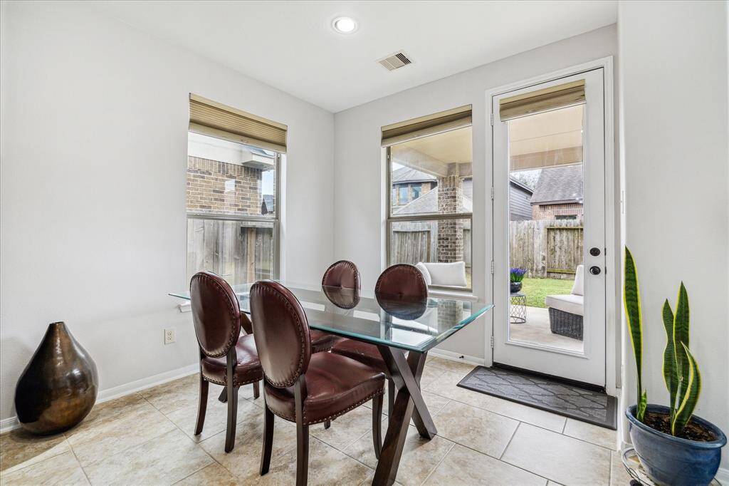 Breakfast area, featuring large windows and a door leading to a cozy covered outdoor patio.