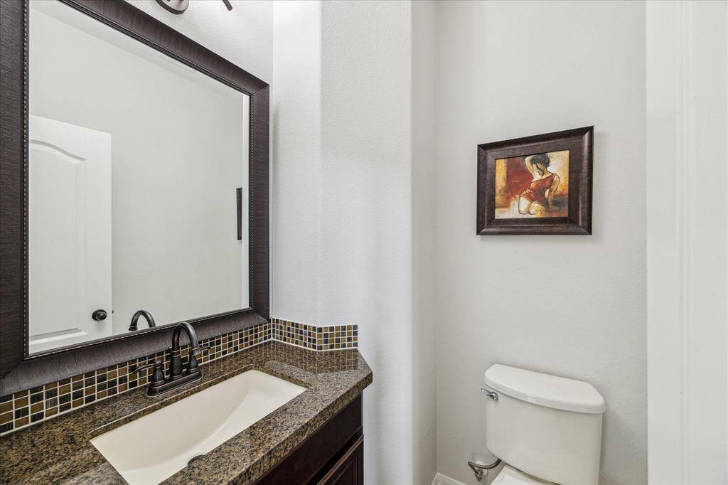 Half bathroom featuring a granite countertop with a modern undermount sink and a sleek, dark-framed mirror.