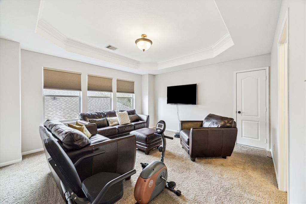 Upstairs Game room boasting tray ceiling, natural lighting, located next to a large attic space with easy access for additional storage.