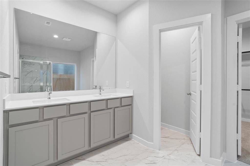 This large primary bath is spacious enough to share! With separate vanities, large closet space, plentiful cabinet and counter space, you are sure to have private area while sharing this bathroom!