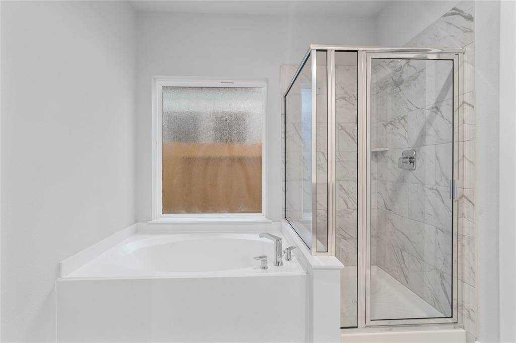 This primary bathroom is definitely move-in ready! Featuring a large garden tub to soak in after a long day, and a framed walk-in shower with tile surround!
