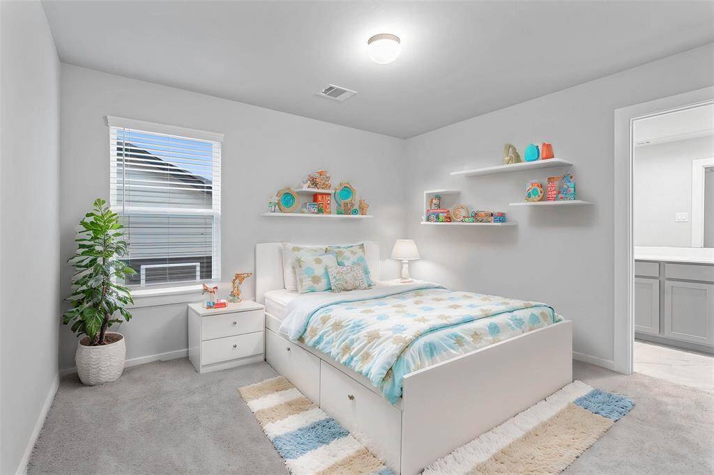 Secondary bedroom features plush carpet, custom paint, high ceilings, large window with privacy blinds, and its own private access to a secondary bathroom.