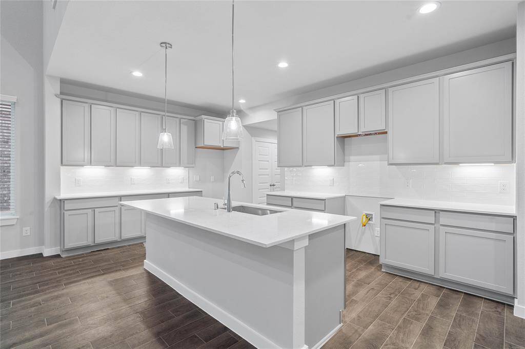 This kitchen is by far any chef’s dream! This spacious kitchen features high ceilings, recessed lighting, pendant lighting, stained wood cabinets, quartz countertops, modern tile backsplash, kitchen island with extended bartop, and single bowl stainless steel sink, and a pantry all overlooking your huge family room.