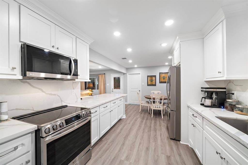 The gourmet kitchen features sleek quartz countertops with an elegant marbled pattern, offering a modern yet timeless appeal. Crisp white cabinetry with brushed nickel hardware provides ample storage, while recessed lighting creates a bright and inviting space.