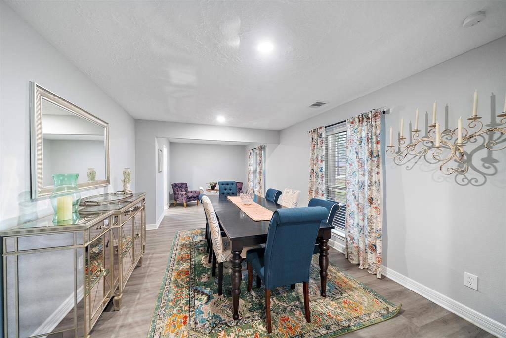 The spacious dining room is designed for both intimate dinners and large gatherings, featuring updated flooring and fresh neutral paint that enhances the room’s airy feel.