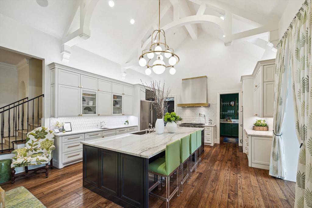 The trussed beamed soaring ceiling is a focal point you cannot miss. This chef’s kitchen, which was remodeled in 2017, features top of the line appliances: Dacor 6 burner gas range, refrigerator and freezer, wall ovens and warming drawers. There are two Thermador dishwashers as well. The designer vent hood made of stainless steal and brass pops against the sleek white background and compliments the chandeliers.