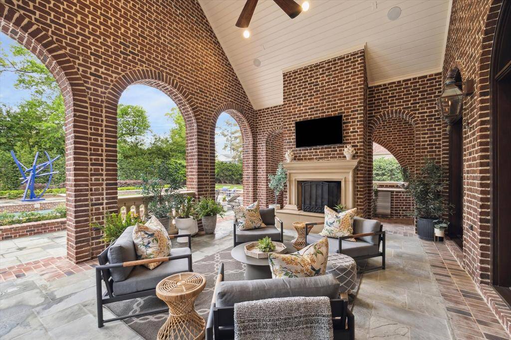 At the end of the gallery hallway and directly off of the sunroom, you will find the covered loggia and summer kitchen. There’s also a pool half bath. Graceful archways appear to be picture frames for the pool and green spaces. The limestone mantle, gas lanterns and Georgian brick and flagstone are a few examples of how the custom finishes and quality of design continue outdoors.