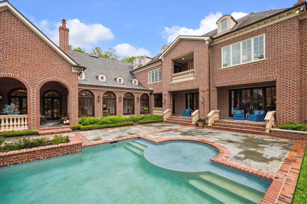 Pool view of the Georgian brick facade, stone balcony, slate roof and covered porches. Wow!