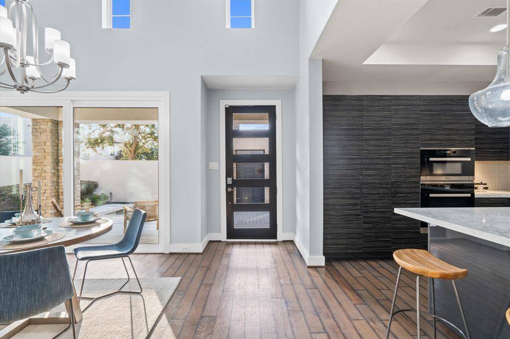 A sleek, dark-framed glass front door adds a touch of sophistication, while large sliding glass doors provide a seamless connection to the outdoor space