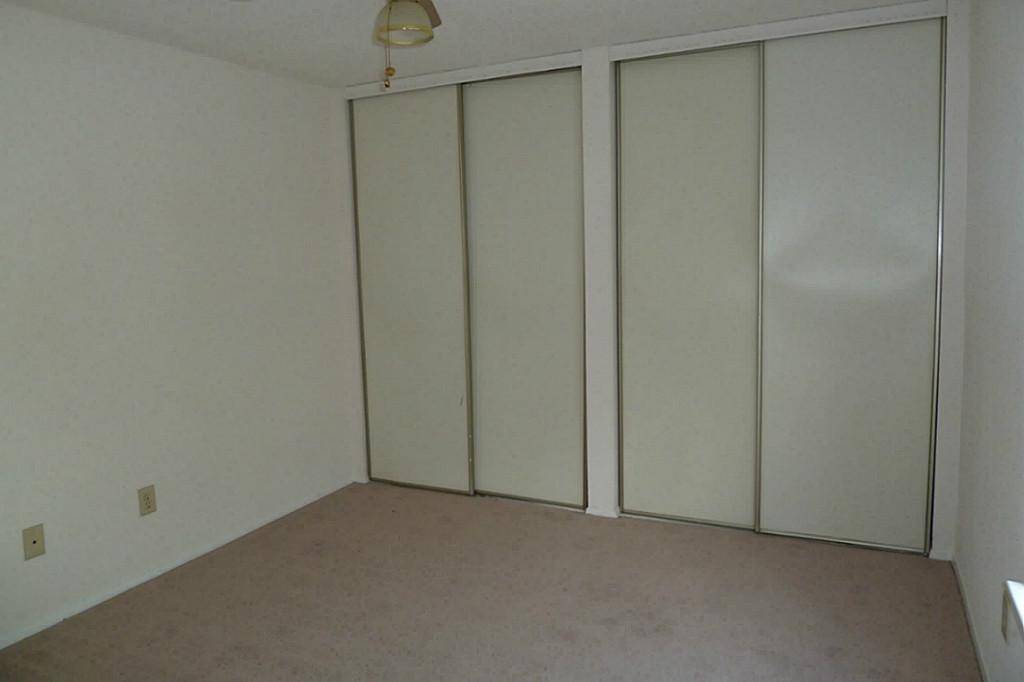 Second floor bedroom with wall of closets and neutral paint and wood vinyl flooring (carpet has been replaced).