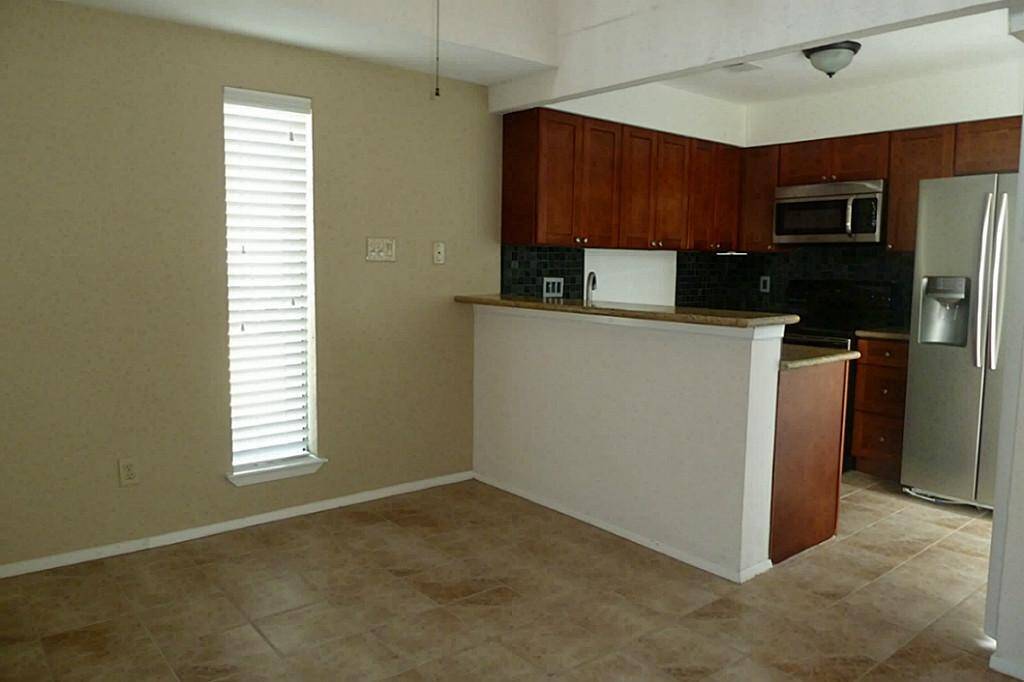 View of dining area and open kitchen with tile flooring and breakfast bar.