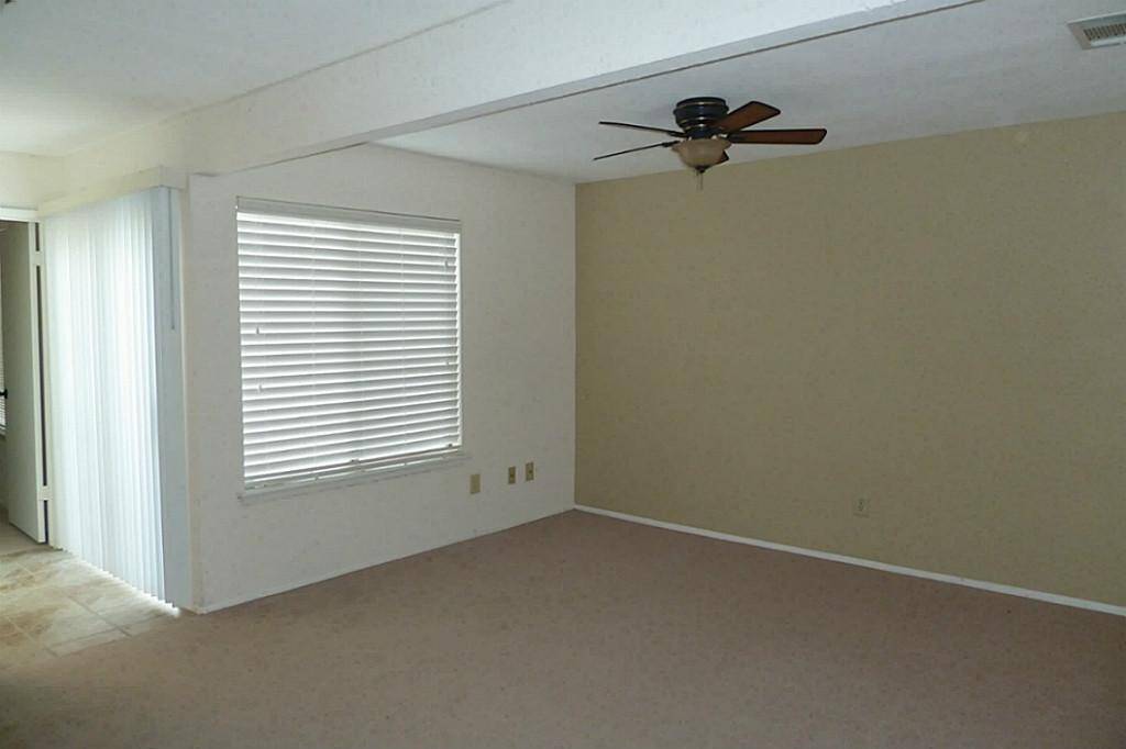First floor bedroom is off the living room with recent paint, vinyl wood flooring (carpet has been replaced with vinyl)and window blinds.