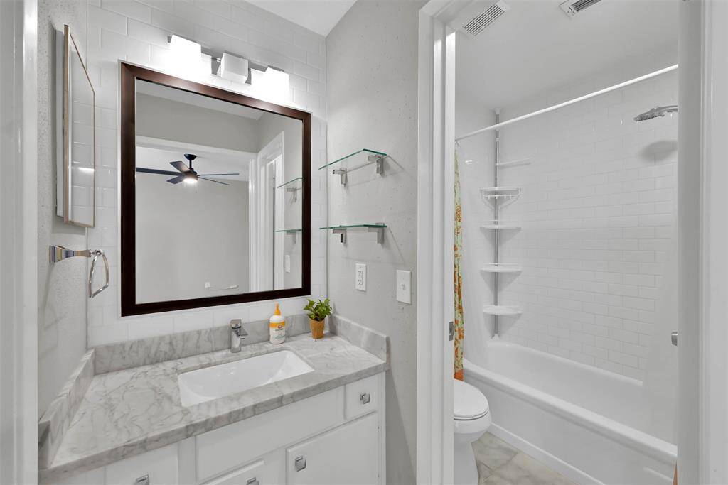 Secondary bedroom's bath with tub/shower combo and a walk in closet to left of the sink.