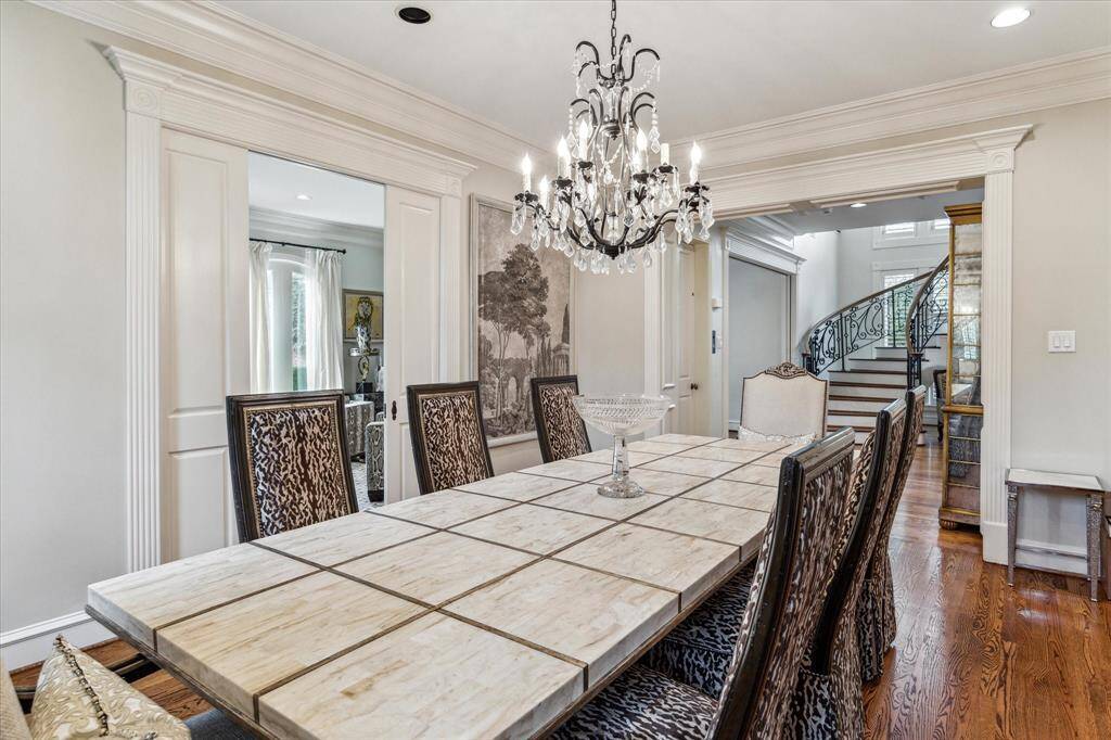 This formal dining room is a blend of elegance and charm, featuring warm hardwood flooring and an antique chandelier that adds a touch of vintage sophistication. Expansive windows with eastern exposure flood the space with natural light, complemented by custom window coverings, recessed LED lighting, and custom crown molding. In-ceiling speakers create the perfect ambiance for intimate dinners and gatherings.