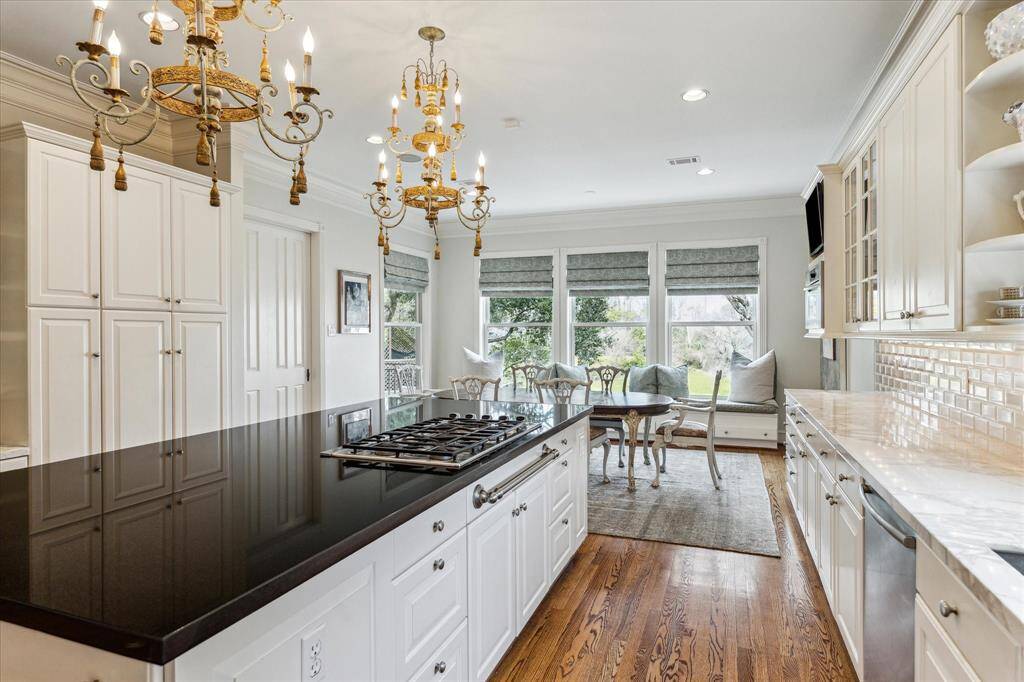 This luxurious kitchen is a chef's dream, featuring KitchenAid double wall ovens, a DCS gas cooktop, and a SubZero 36” refrigerator and freezer. Marble perimeter countertops and a black granite island provide a stunning contrast, while upper and lower cabinetry offers ample storage with under- cabinet lighting for added convenience.