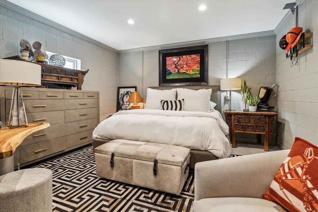 This spacious lower level bedroom is bathed in natural light and neutral finishes. With designer neutral tile flooring, recessed LED lighting, ensuite bath, and convenient access to the lower level utility room and three-car garage, this space combines both practicality and style.