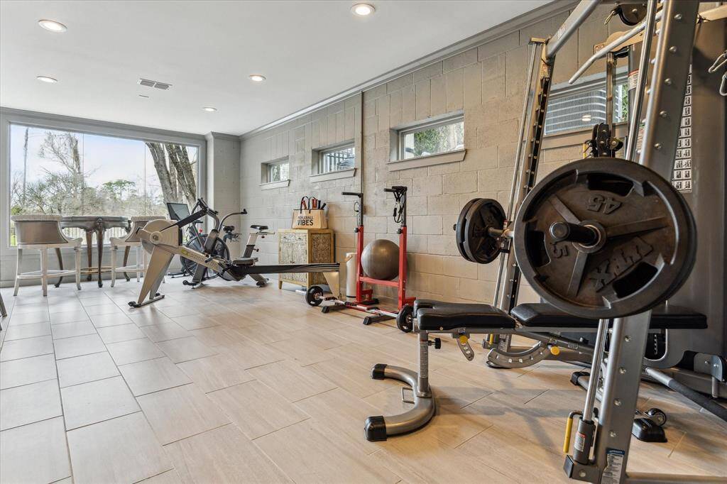The inviting lower-level space offers versatile flex use, perfect for a gym or game room to suit your needs. This space offers seamless access to the pool area and backyard, providing the perfect space for indoor-outdoor living and entertaining. Expansive windows offer stunning views of the pool and backyard, while recessed LED lighting and designer tile flooring enhance the room’s stylish and functional atmosphere.
