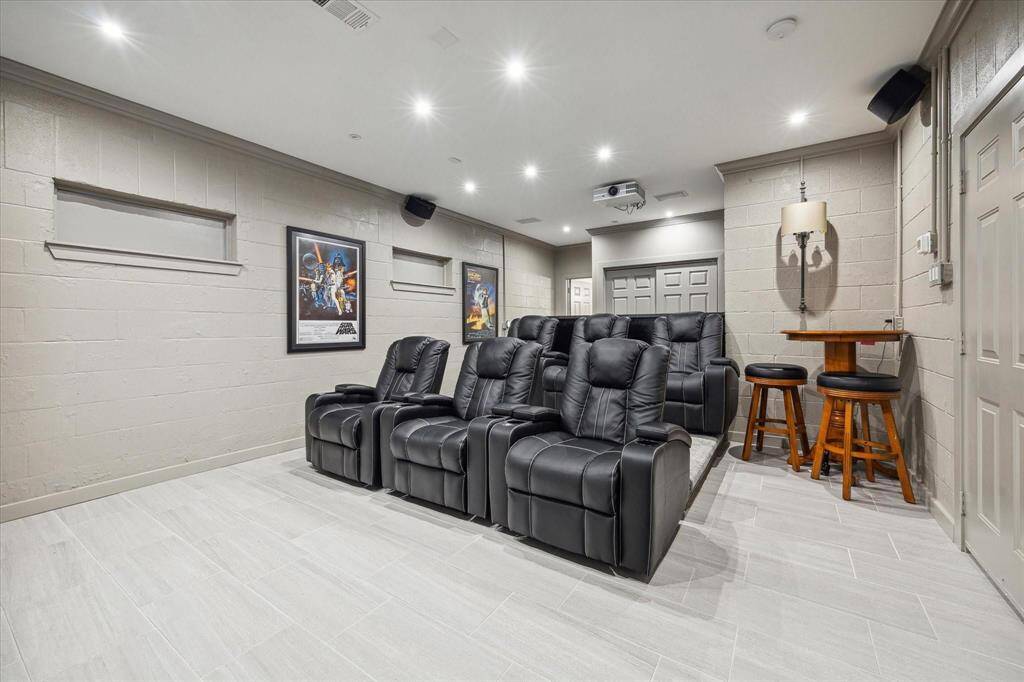 This luxurious lower level media room features dual levels designed for optimal viewing, offering the perfect setup for an immersive cinematic experience. A trio of designer sconces casts a warm glow, complemented by recessed LED lighting with dimmer switches, allowing for customized ambiance. With designer neutral tile flooring, sophisticated wall paint, and convenient access to a lower level full bathroom, this space is both stylish and functional for extended entertainment.