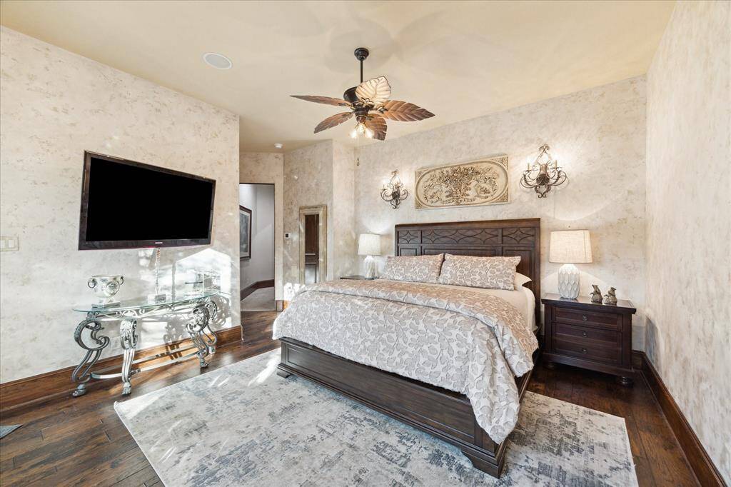 An elegant guest bedroom that  can accomodate a kingsize bed and boasts stylish wall sconces,and a modern ceiling fan,  The room has rich hardwood floors and a textured wall finish, creating a warm and inviting atmosphere.