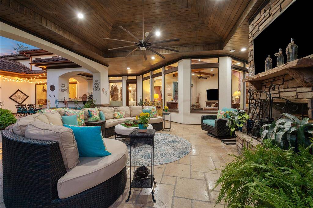 This is another view of the covered outdoor living area with comfortable seating, a fireplace, warm lighting, and an open layout connecting seamlessly to the indoors.