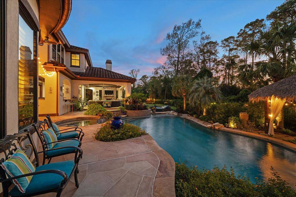 Views of the outdoor entertainment area with a well-designed pool, mature landscaping, and cozy seating, perfect for enjoying the serene twilight ambiance.