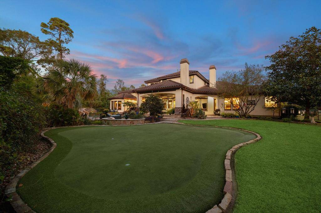 Enjoy the personal putting green in the backyard, with lush landscaping and a tranquil twilight sky.