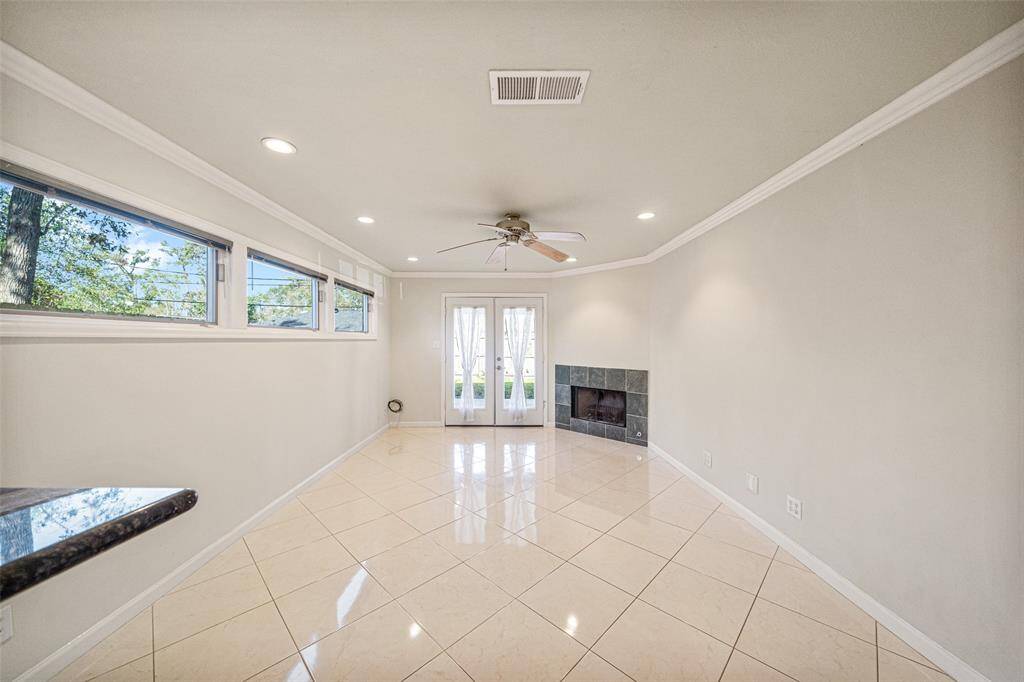 A stunning living room featuring sleek tile flooring, an abundance of windows that flood the space with natural light, a cozy fireplace, and seamless access to the backyard and patio—perfect for indoor-outdoor living!