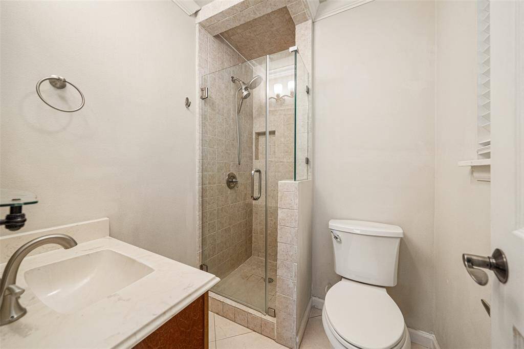 The primary bath features a glass-enclosed shower and vanity with storage offering a sleek and modern touch to your daily routine.